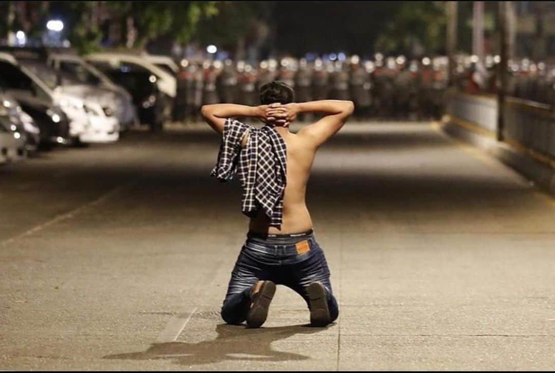 トーマス・サドスキーのインスタグラム：「A demonstrator kneels in protest against the military coup while riot police prepare to advance in Yangon, #Myanmar, 25 February.  #FreeMyanmar.   📷: EPA-EFE/NYEIN CHAN NAING」