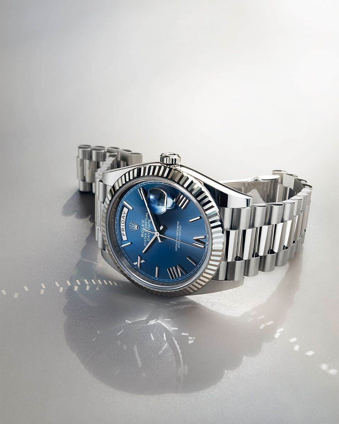rolexのインスタグラム：「The Day-Date 40 in 18ct white gold with a bright blue dial, Roman faceted numerals and a fluted bezel. The arc-shaped window at 12 o’clock on the dial, indicating the day of the week in full, is the hallmark of the Day-Date's visual identity, an intrinsic celebration of each new dawn. #Rolex #DayDate #101031」